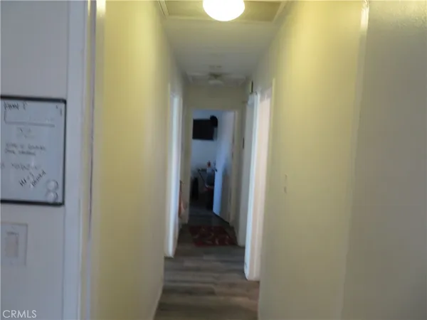 a view of a hallway with wooden floor and a bathroom