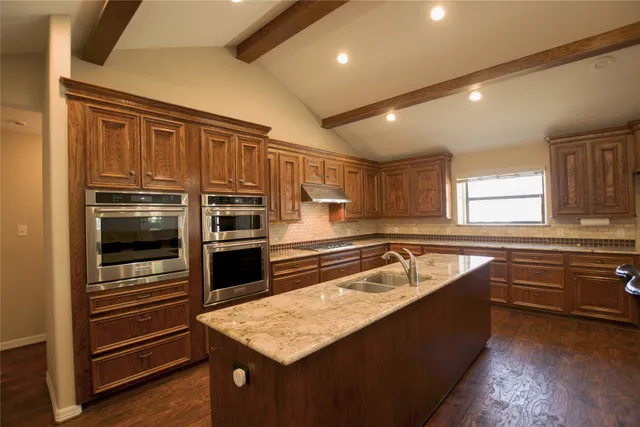 a kitchen with kitchen island granite countertop a stove and cabinets