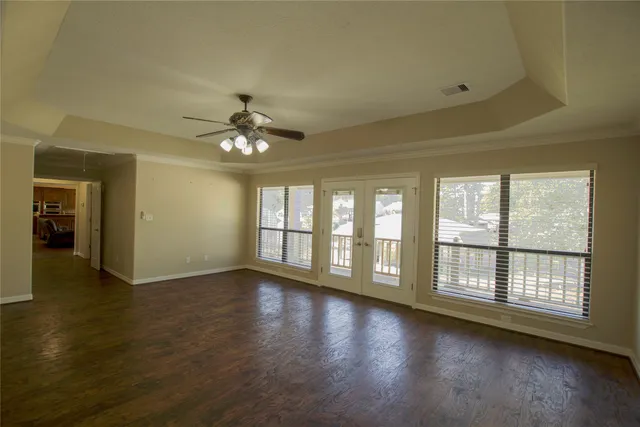 a view of an empty room with wooden floor and a window