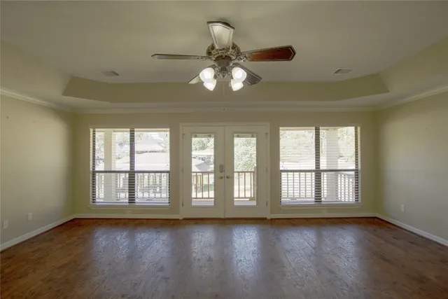 a view of empty room with wooden floor and fan
