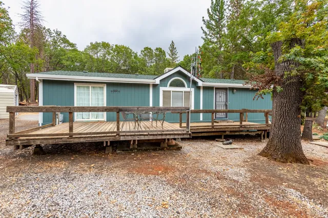a view of a house with a backyard and a wooden deck