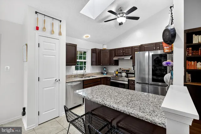 a kitchen with stainless steel appliances granite countertop a refrigerator a stove and white cabinets with wooden floor