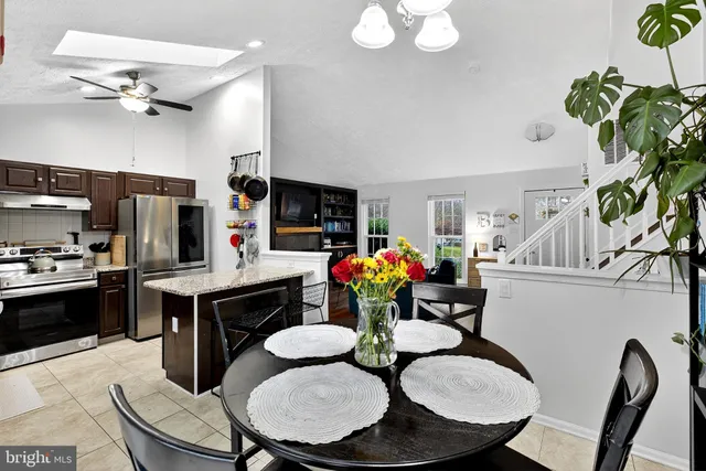 a kitchen with granite countertop a dining table chairs stainless steel appliances and cabinets
