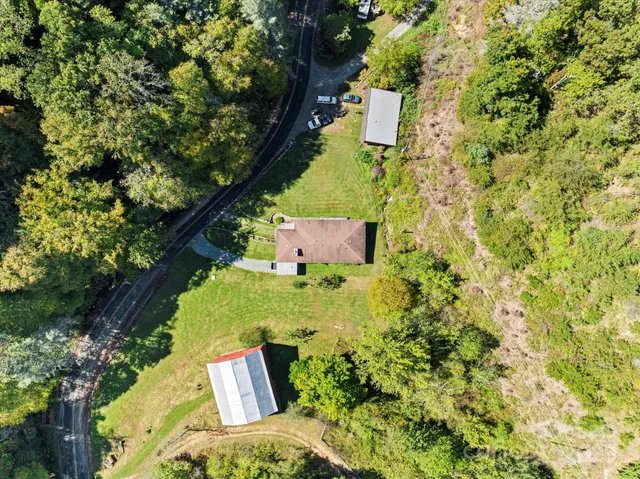 an aerial view of residential house with outdoor space and trees all around