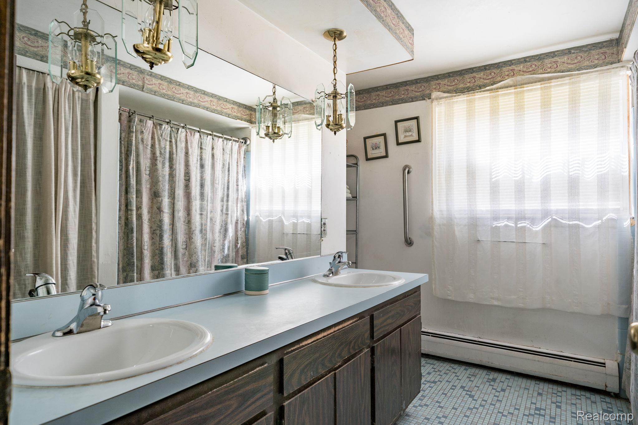 19650 Midway Road Southfield, MI 48075 - Photo 21 of 30 Full bathroom featuring double vanity, a baseboard heating unit, light tile patterned flooring, a chandelier, and a shower with shower curtain