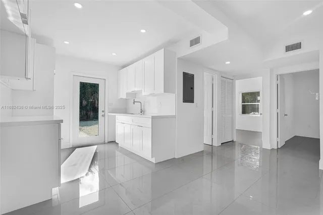 a large white kitchen with stainless steel appliances cabinets and a sink