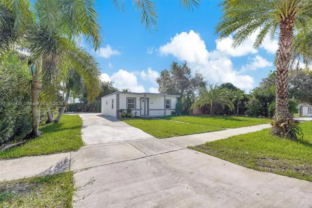 a view of a house with a big yard potted plants and large trees