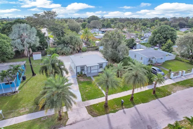an aerial view of residential houses with outdoor space and trees