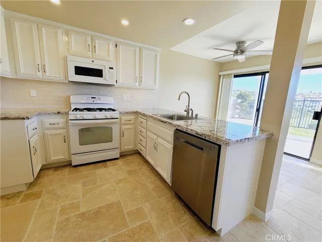 an empty room with chandelier fan and windows