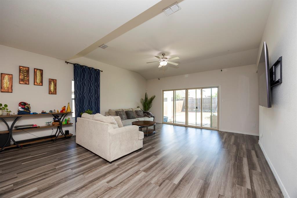 495 Fox Ridge Drive Princeton, TX 75407 - Photo 13 of 31 Spacious living area featuring wood-finish flooring, a ceiling fan, and sliding glass doors