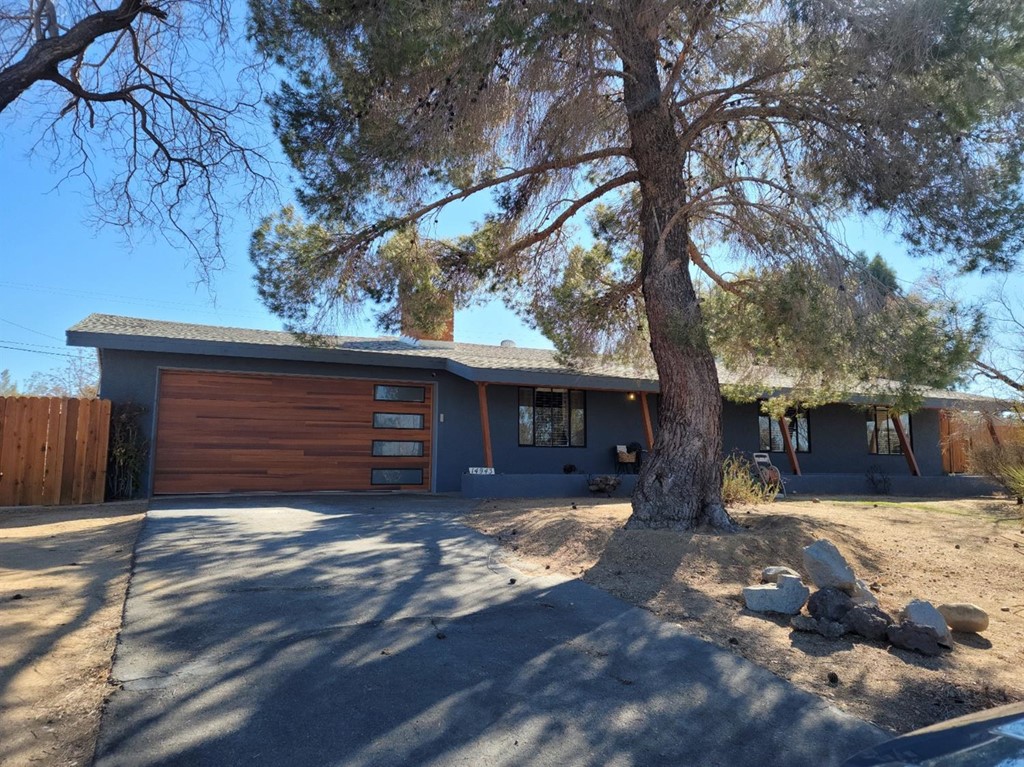 14943 Tacony Road Apple Valley, CA 92307 - Photo 1 of 1 a view of a house with a yard tree and wooden fence