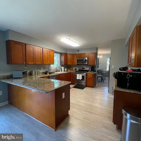 a kitchen with stainless steel appliances granite countertop a stove top oven a sink dishwasher and a microwave oven on the wooden floor