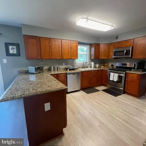 a kitchen with stainless steel appliances granite countertop a stove a sink dishwasher and a refrigerator