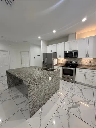 a kitchen with granite countertop white cabinets and stainless steel appliances