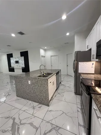 a large white kitchen with a large counter top and stainless steel appliances