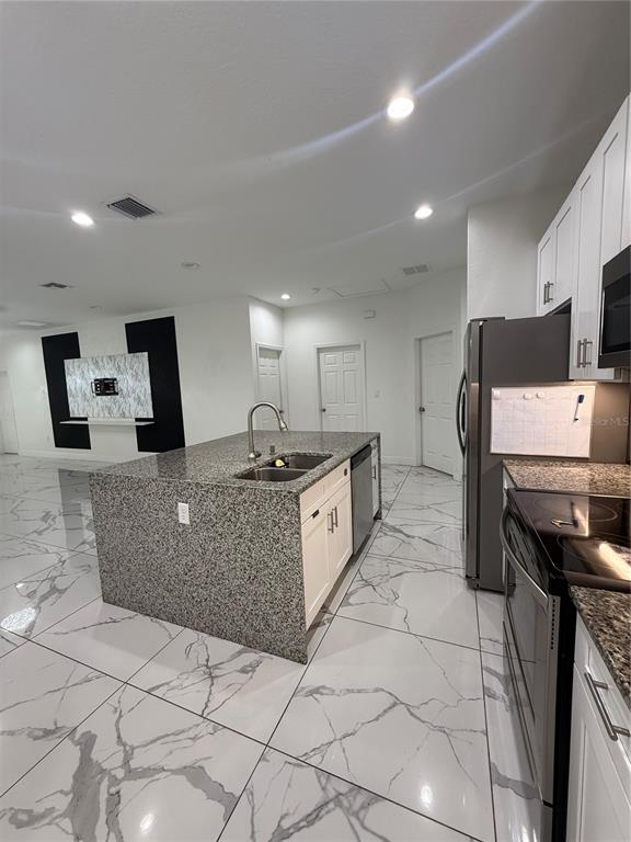 310 Grape Avenue St. Cloud, FL 34769 - Photo 15 of 27 a large white kitchen with a large counter top and stainless steel appliances
