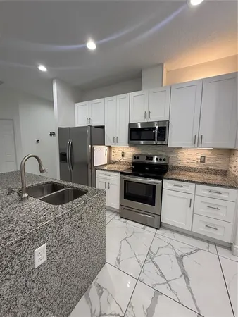 a kitchen with granite countertop a stove and a refrigerator