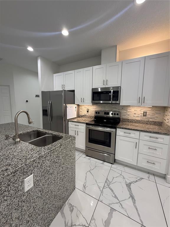 310 Grape Avenue St. Cloud, FL 34769 - Photo 16 of 27 a kitchen with granite countertop a stove and a refrigerator
