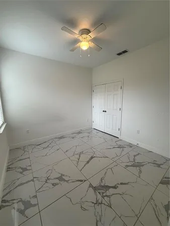 a view of an empty room and chandelier fan