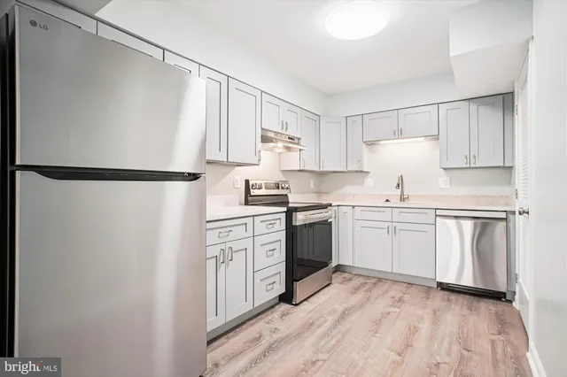 a kitchen with a refrigerator a sink and white cabinets