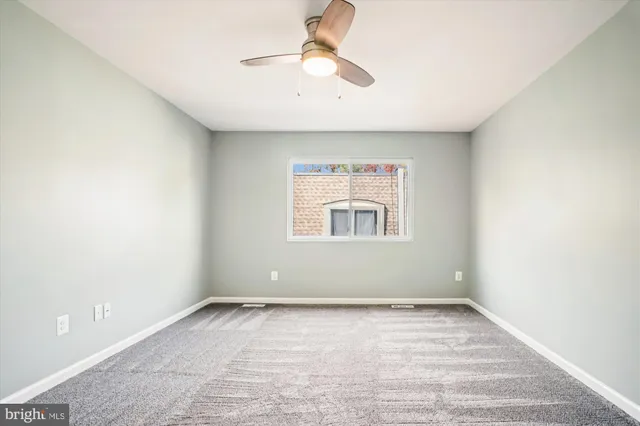 an empty room with chandelier fan and windows