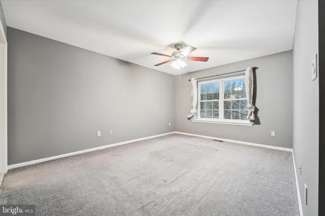 an empty room with windows and ceiling fan
