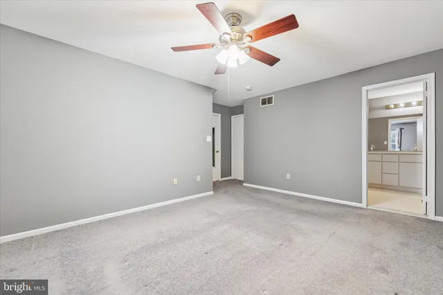 an empty room with closet and a ceiling fan