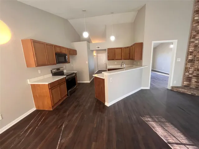 a kitchen with stainless steel appliances a microwave a stove a sink a refrigerator wooden floor and cabinets