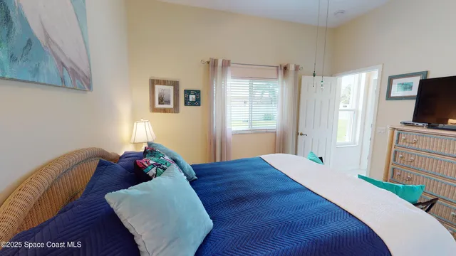 a bed room with a bed television and a window