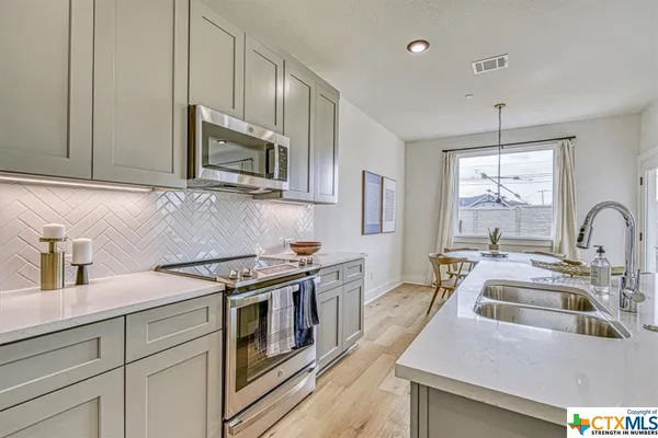 a kitchen with stainless steel appliances granite countertop a stove a sink and a microwave