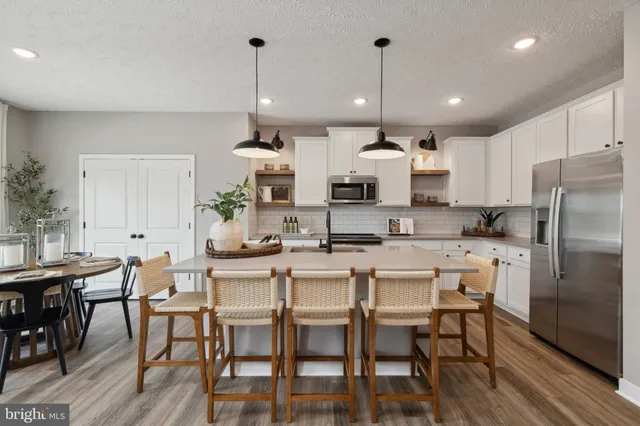 a kitchen with stainless steel appliances kitchen island granite countertop a dining table chairs and white cabinets