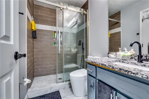 a bathroom with a granite countertop sink a toilet and shower