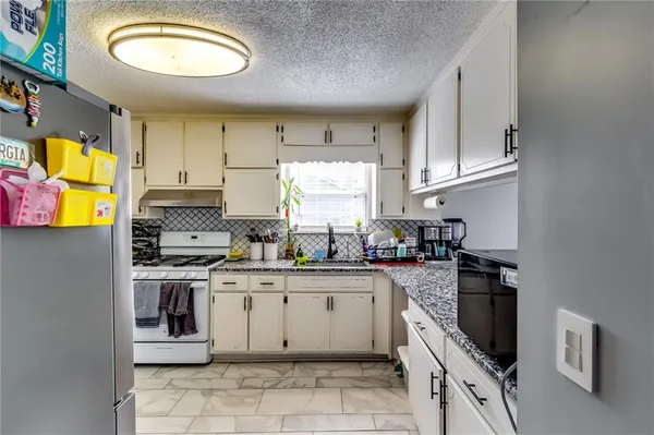 a kitchen with stainless steel appliances granite countertop a stove a sink and a refrigerator