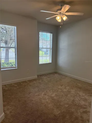 an empty room with windows and fan