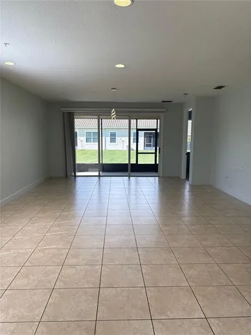an empty room with windows and chandelier fan