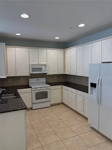 a kitchen with granite countertop white cabinets and stainless steel appliances
