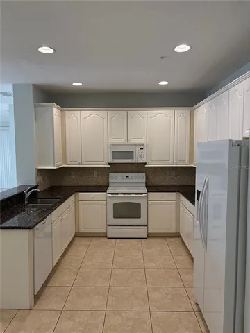 a white kitchen with granite top and stainless steel appliances