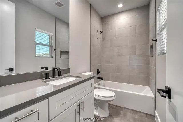 a bathroom with a granite countertop sink a toilet and shower