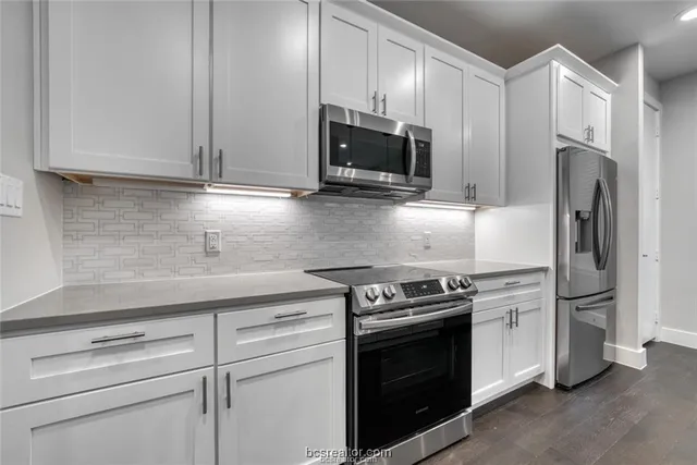a kitchen with stainless steel appliances white cabinets white stove a microwave and a refrigerator