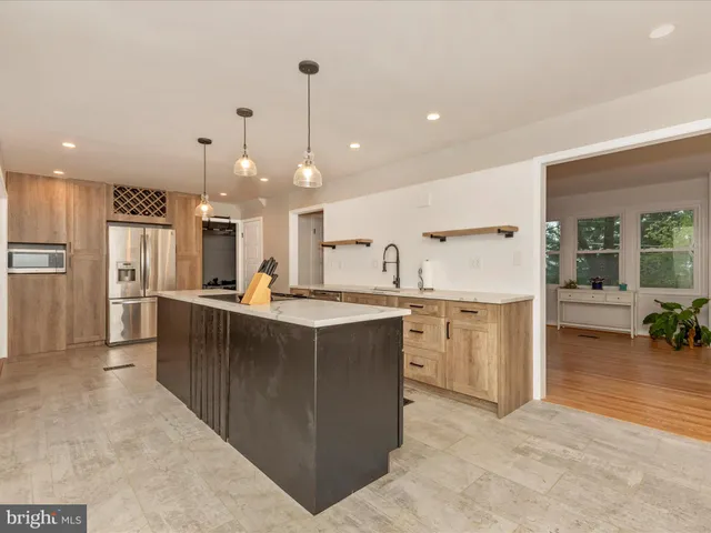 a large kitchen with kitchen island a large counter top stainless steel appliances and cabinets