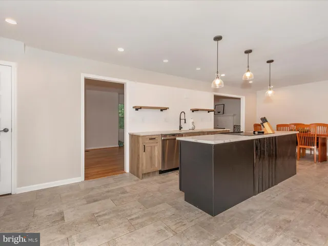 a large kitchen with a large counter top a sink a counter space and stainless steel appliances