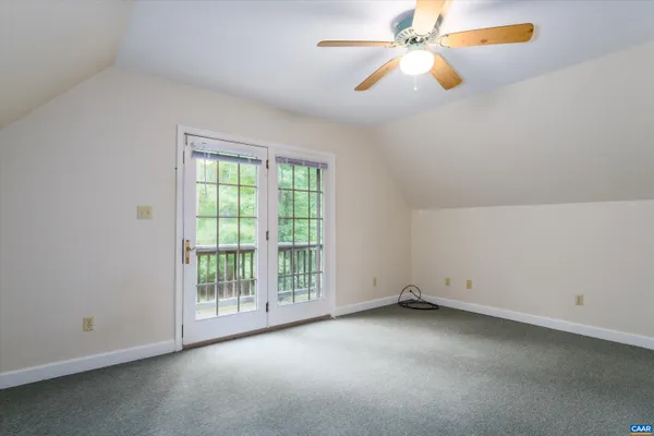 an empty room with chandelier fan and windows