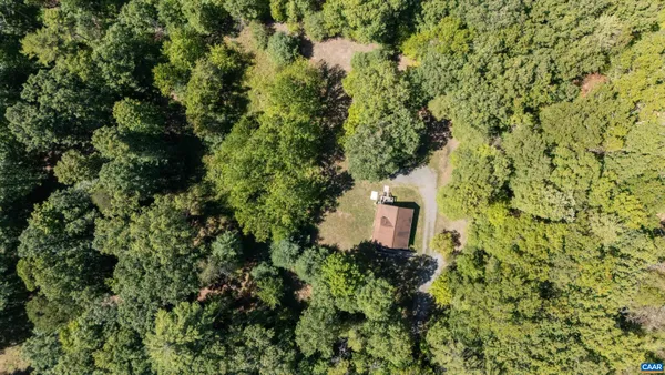 an aerial view of residential house with outdoor space and trees all around