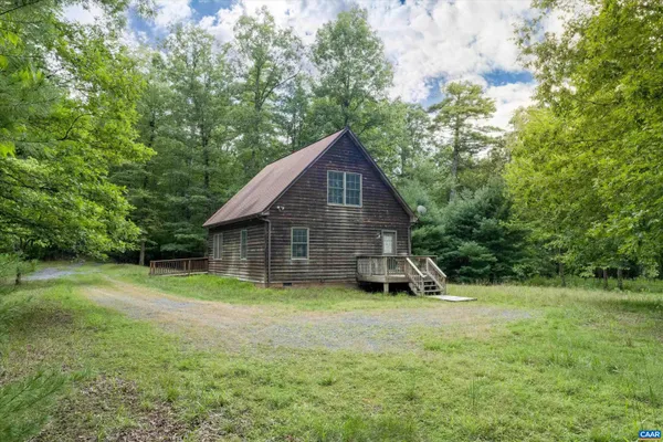 a view of a house with a yard and large trees