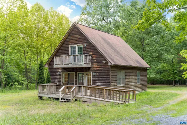 a backyard of a house with wooden deck and outdoor seating