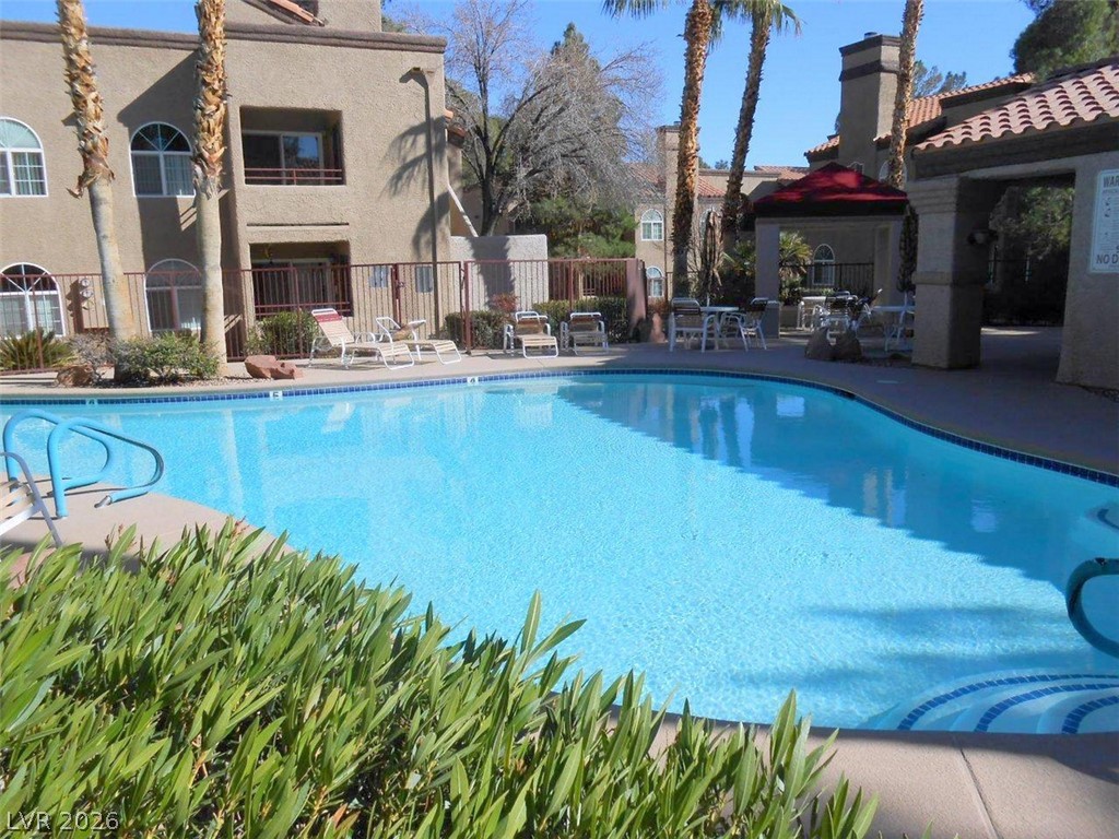 9325 West Desert Inn Road, Unit 132 Las Vegas, NV 89117 - Photo 22 of 36 An inviting community pool beckons on a clear day, surrounded by tropical landscaping and comfortable lounging areas.