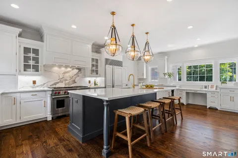 a kitchen with stainless steel appliances granite countertop wooden floor window and chairs