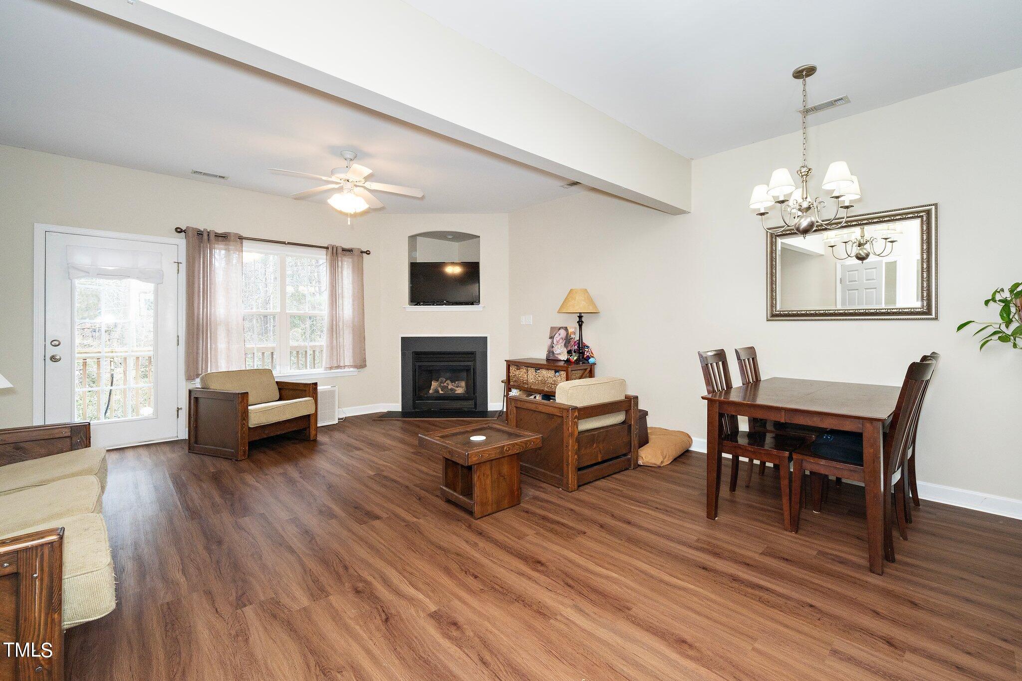 4602 Centrebrook Circle Raleigh, NC 27616 - Photo 7 of 24 a living room with furniture a fireplace and a dining table with wooden floor
