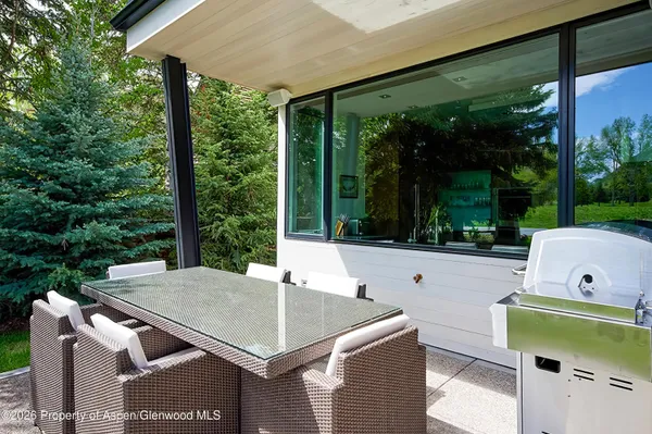 a view of a patio with table and chairs under an umbrella with a small yard