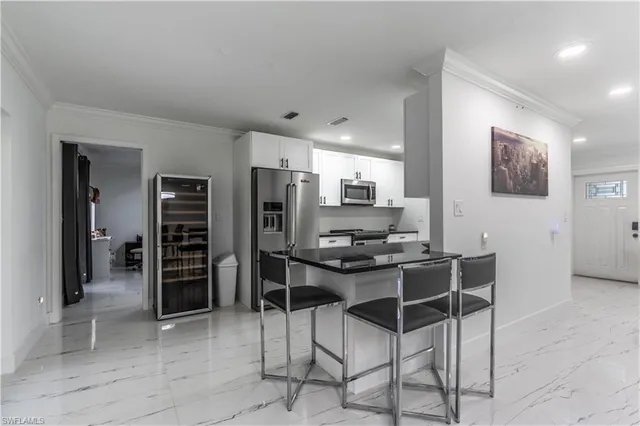 a kitchen with stainless steel appliances kitchen island granite countertop a refrigerator and cabinets